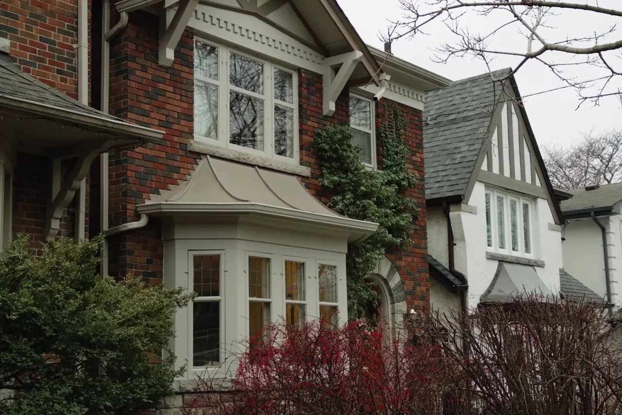 Two storey brick house with bay windows on a Toronto street in winter