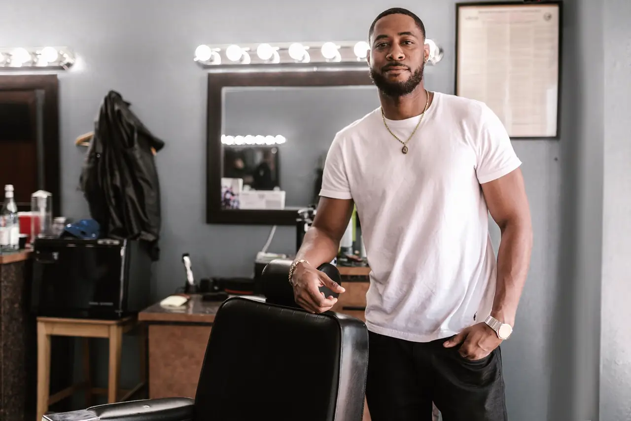 Barber stands beside the chair in his own modern barbershop